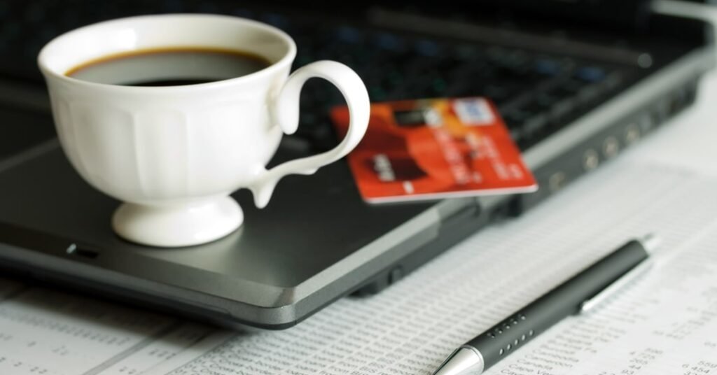 Visual with coffee cup, laptop, and credit card portraying e-money industry