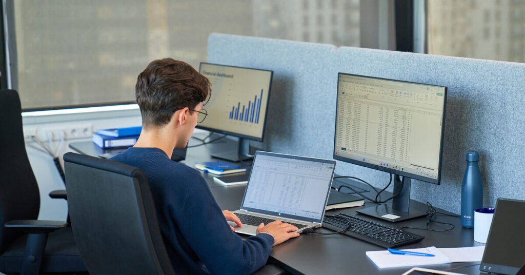 a man, working at Baltic Assist, sitting behind a desk, reviewing data on computer.