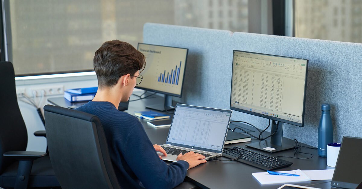a man, working at Baltic Assist, sitting behind a desk, reviewing data on computer.