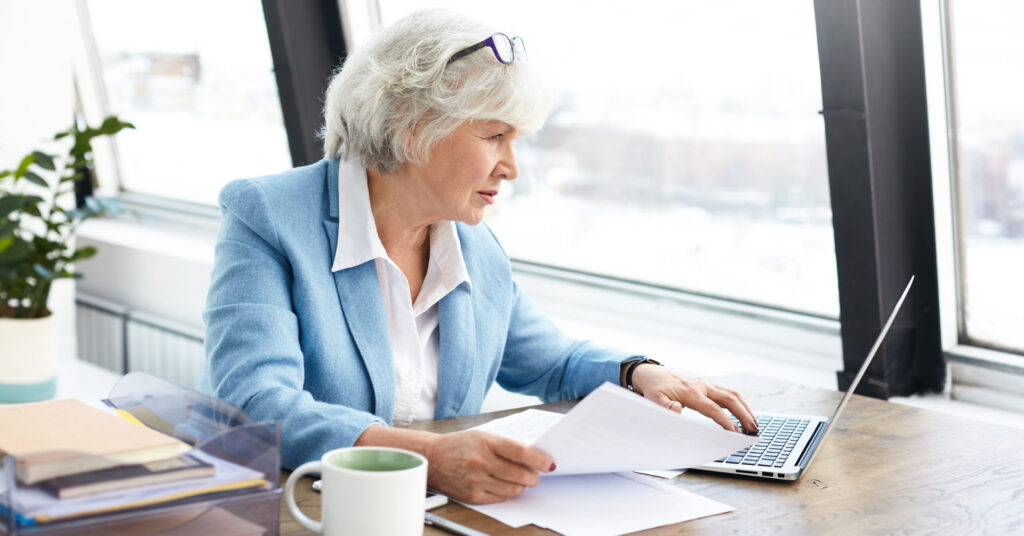 successful experienced elderly female lawyer wearing nice suit glasses her head using portable computer her workplace looking screen with focused concentrated facial expression scaled e1751616065510